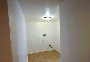 Washroom with electric dryer hookup, light tile patterned floors, and hookup for a washing machine