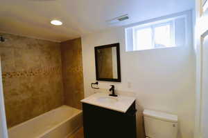 Full bathroom with vanity, toilet, and tiled shower / bath