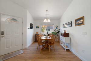 Dining room with light hardwood / wood-style floors and an inviting chandelier