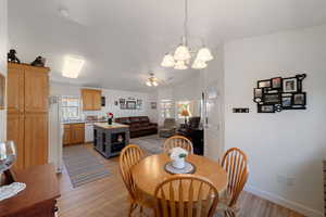 Dining space featuring lofted ceiling, sink, ceiling fan with notable chandelier, and light wood-type flooring