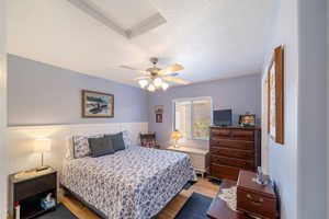 Bedroom with ceiling fan, light hardwood / wood-style flooring, and a textured ceiling