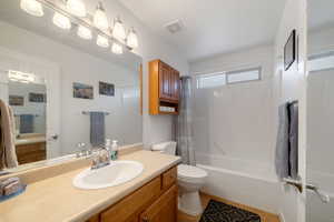 Full bathroom with hardwood / wood-style floors, vanity, shower / bath combo, and toilet