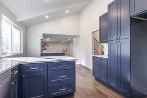 Kitchen with blue cabinetry, lofted ceiling with beams, wooden ceiling, and dark wood-type flooring