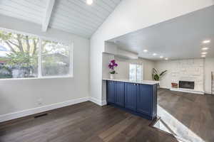 Interior space with a fireplace, dark hardwood / wood-style floors, blue cabinets, and lofted ceiling