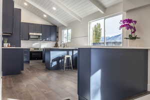 Kitchen with a mountain view, kitchen peninsula, appliances with stainless steel finishes, wood-type flooring, and a breakfast bar area