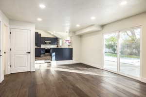 Interior space featuring a textured ceiling, vaulted ceiling, and dark hardwood / wood-style floors