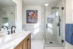 Bathroom with tile walls, vanity, an enclosed shower, and toilet