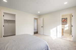 Carpeted bedroom featuring a spacious closet, ensuite bath, and a closet