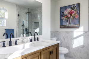 Bathroom featuring vanity, an enclosed shower, tile walls, and toilet