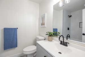 Bathroom with a tile shower, vanity, and toilet