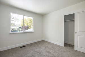 Unfurnished bedroom with light carpet and a closet