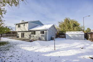 Snow covered rear of property with an outbuilding