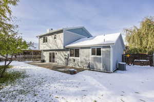 Snow covered rear of property featuring central AC