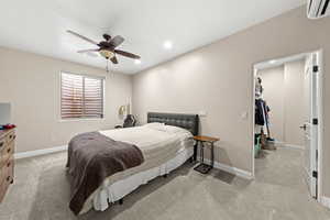 Bedroom featuring ceiling fan, a spacious closet, a wall mounted AC, light colored carpet, and a closet