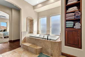 Bathroom with tiled bath, ceiling fan, and hardwood / wood-style floors