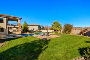 View of yard with a patio, a balcony, ceiling fan, and a fenced in pool