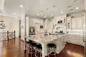 Kitchen featuring a large island, dark hardwood / wood-style flooring, decorative light fixtures, and sink