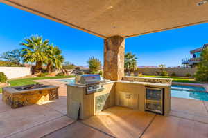 View of patio with a fenced in pool, wine cooler, a grill, and area for grilling