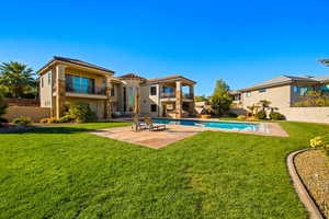 Rear view of house featuring a yard, a balcony, and a patio