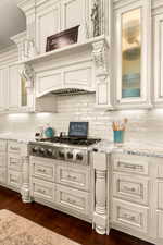 Kitchen featuring stainless steel gas stovetop, light stone counters, ornamental molding, and dark wood-type flooring