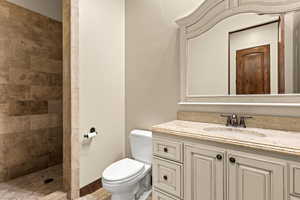 Bathroom featuring a tile shower, vanity, and toilet