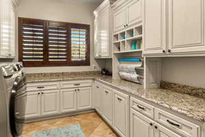 Washroom with cabinets, light tile patterned floors, and separate washer and dryer