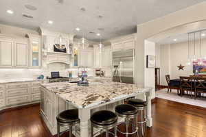 Kitchen featuring sink, a center island, dark wood-type flooring, pendant lighting, and appliances with stainless steel finishes