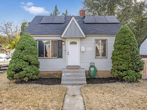 Bungalow-style house featuring solar panels and a front yard