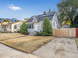 View of front of house with a mountain view, solar panels, and a front lawn