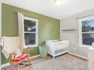 Bedroom featuring a nursery area, light hardwood / wood-style floors, and multiple windows