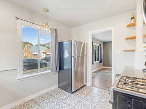 Kitchen featuring pendant lighting, an inviting chandelier, light wood-type flooring, white range with gas stovetop, and stainless steel refrigerator