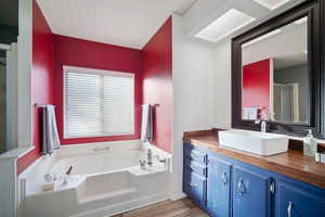 Bathroom with a bath, shower, vanity, and laminate flooring