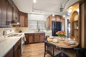 Kitchen with sink, light hardwood / wood-style flooring, pendant lighting, track lighting, and white appliances