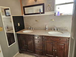 Bathroom with tile patterned flooring, vanity, and tile walls