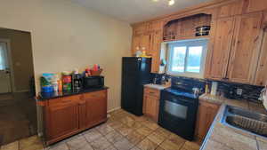 Kitchen with decorative backsplash, a textured ceiling, sink, black appliances, and tile countertops