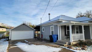 View of front facade featuring covered porch, an outbuilding, and a garage