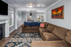 Living room featuring dark hardwood / wood-style floors, ornamental molding, and a tiled fireplace