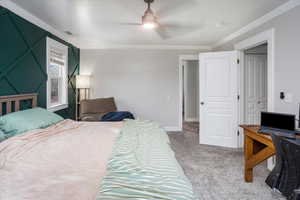 Carpeted bedroom featuring ceiling fan and crown molding