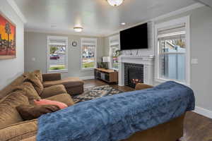 Living room with a tiled fireplace, crown molding, and dark hardwood / wood-style floors