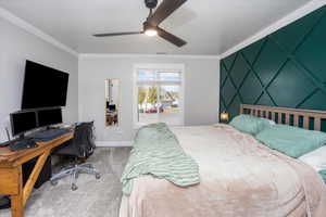 Carpeted bedroom with ceiling fan and crown molding