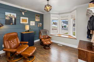 Living area featuring dark hardwood / wood-style flooring, ornamental molding, and wooden walls