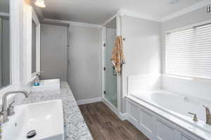 Bathroom with hardwood / wood-style floors, vanity, separate shower and tub, and ornamental molding