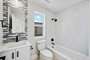 Full bathroom with backsplash, tiled shower / bath, vanity, and toilet