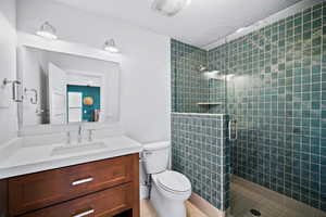 Bathroom with tile patterned floors, walk in shower, a textured ceiling, vanity, and toilet