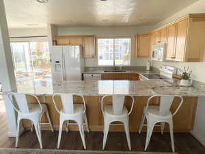 Kitchen featuring LVP floors, white appliances, a textured ceiling, and sink