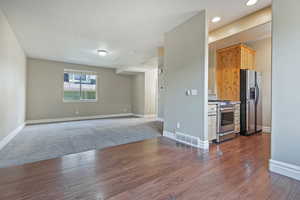 Kitchen with dark hardwood / wood-style floors, light brown cabinets, and stainless steel appliances