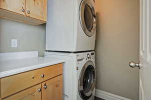 Clothes washing area with cabinets and stacked washer / dryer