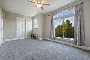 Carpeted empty room with a wealth of natural light and ceiling fan