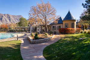 Back of property with a mountain view, a pergola, a fenced in pool, and a lawn