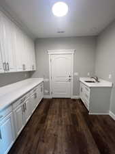 Example Laundry area with dark wood-type flooring and sink